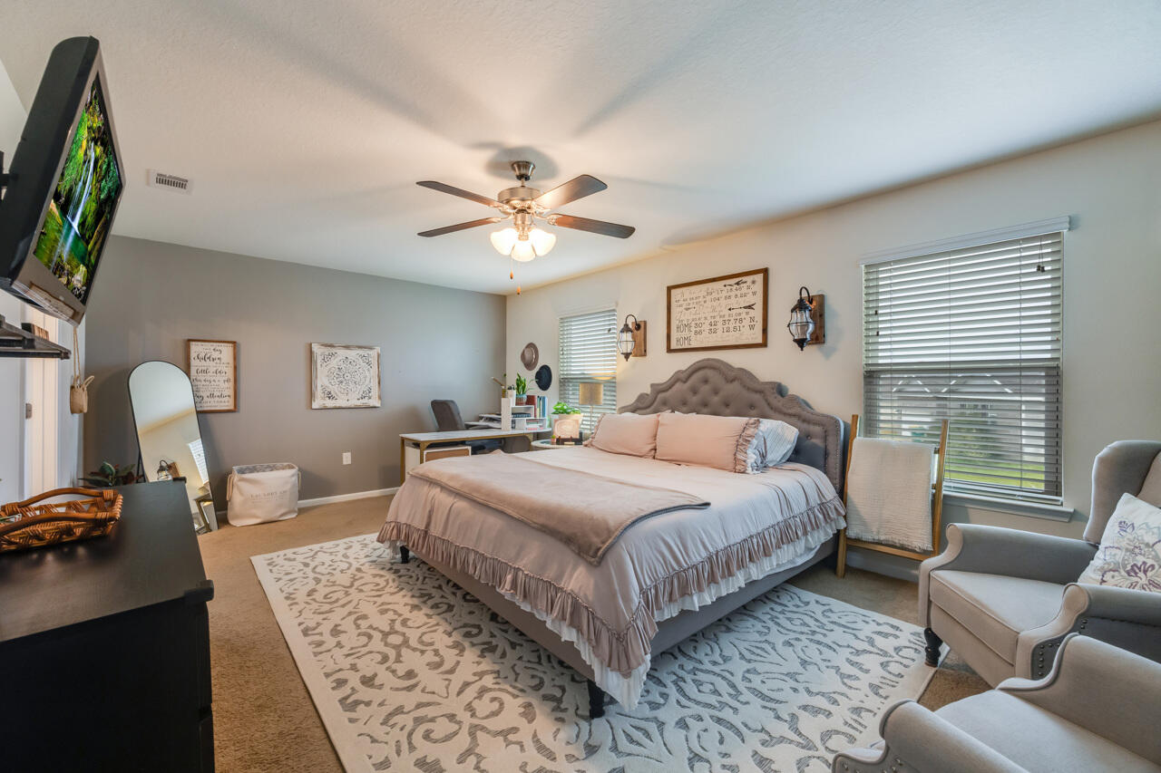 4648 Plover Drive Crestview, FL 32539 - Photo 21 of 71 a spacious bedroom with a bed a couch and a flat tv screen on the dresser