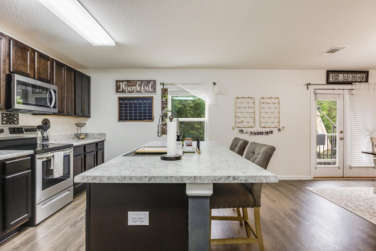 4648 Plover Drive Crestview, FL 32539 - Photo 66 of 71 a kitchen with stainless steel appliances granite countertop a stove top oven a sink dishwasher a dining table and chairs with wooden floor