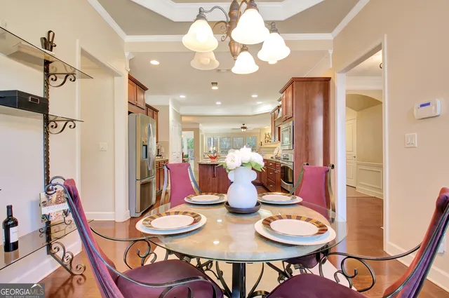 a dining room with wooden floor a chandelier a wooden table and chairs