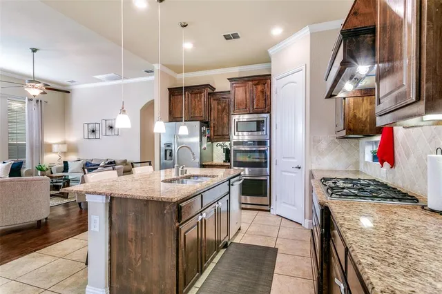 a kitchen with stainless steel appliances kitchen island granite countertop a stove a sink and a refrigerator