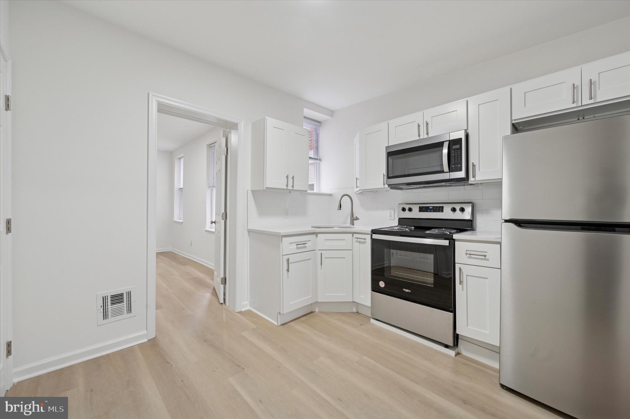 1452 North 56th Street Philadelphia, PA 19131 - Photo 6 of 12 a kitchen with a refrigerator stove and white cabinets