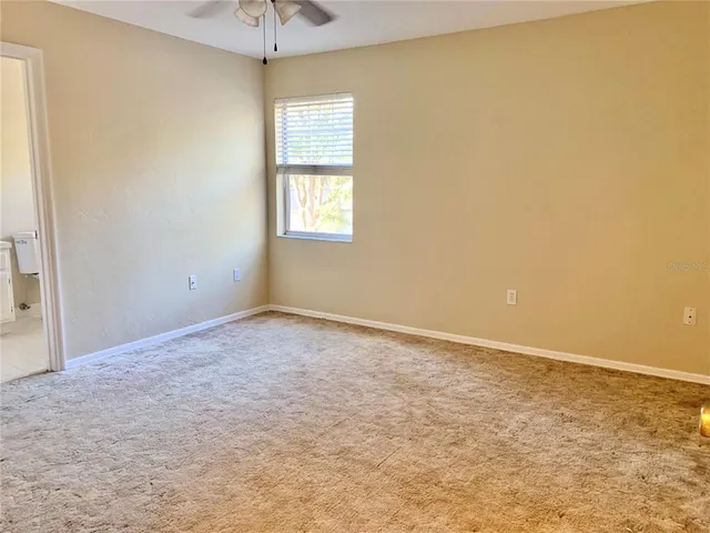 an empty room with a window and a chandelier fan