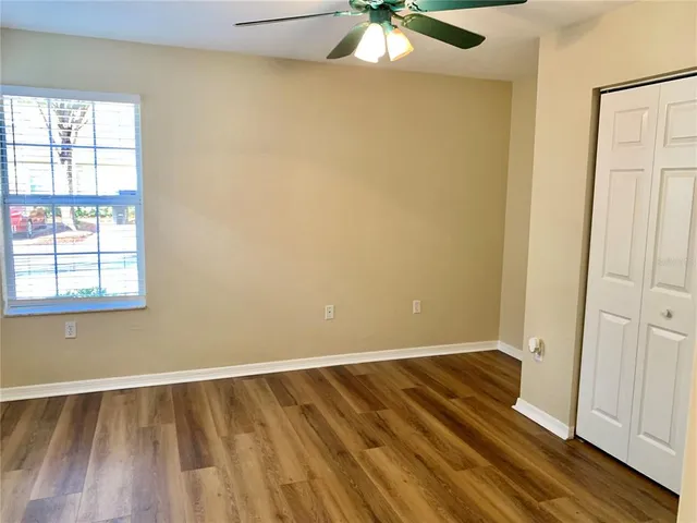 an empty room with wooden floor fan and windows
