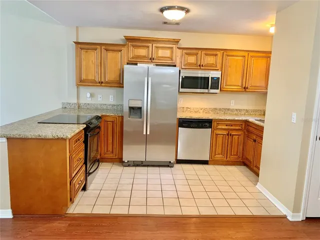 a kitchen with stainless steel appliances granite countertop a refrigerator a sink a stove and island