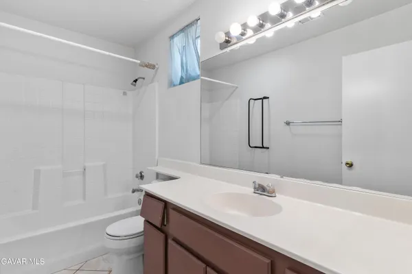 a view of an empty room with wooden floor and a bathroom