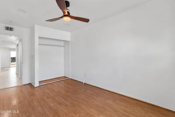 a view of an empty room with wooden floor and closet