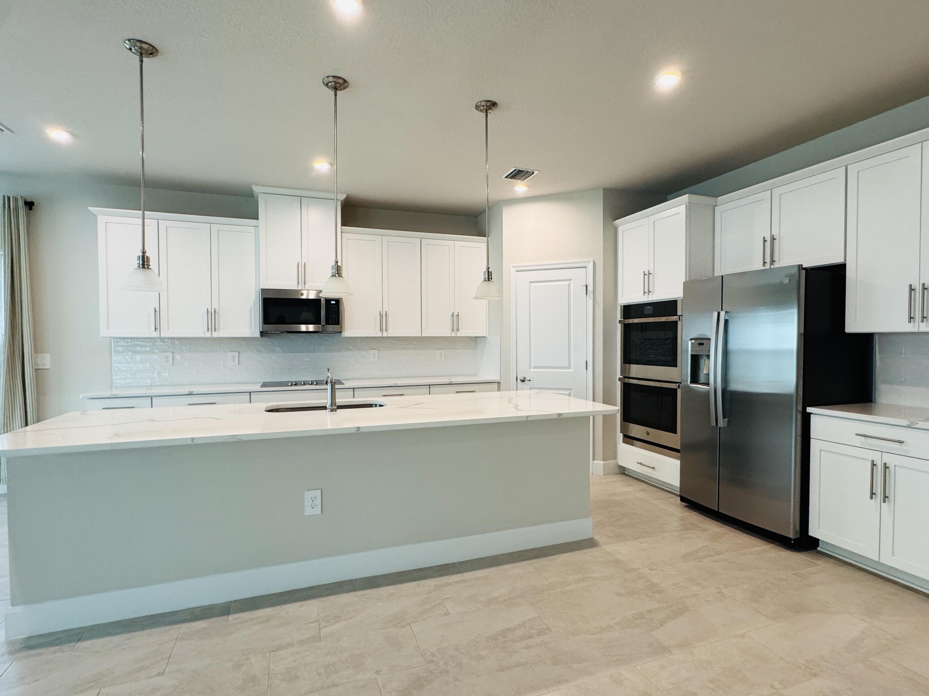 163 Southwest Pomeroy Street Stuart, FL 34997 - Photo 13 of 52 a large kitchen with stainless steel appliances kitchen island granite countertop a refrigerator a stove a sink a island and white cabinets with wooden floor