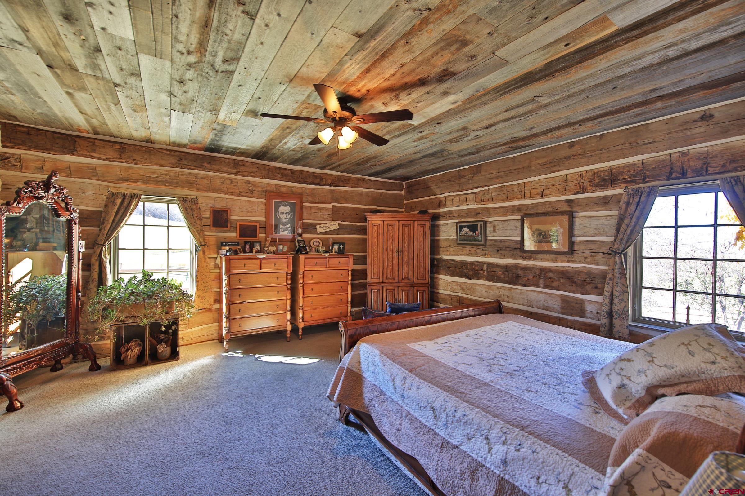 10497 54 7/10 Road Molina, CO 81646 - Photo 13 of 45 a spacious bedroom with a bed a chandelier and a large window with the outer view