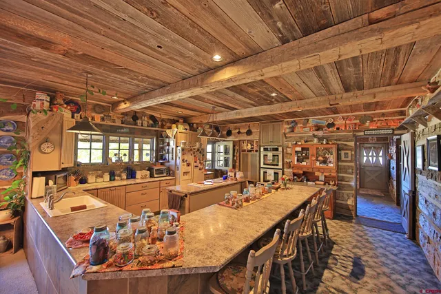 a view of a dining room with furniture a chandelier and kitchen view