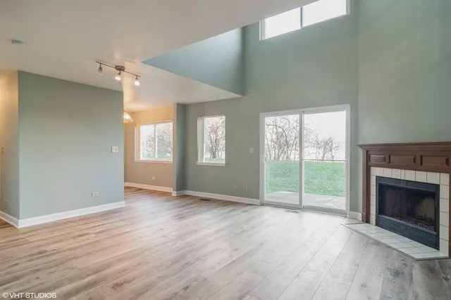 an empty room with wooden floor fireplace and windows