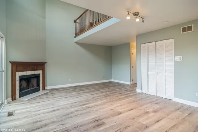 a view of an empty room with wooden floor fireplace and a window
