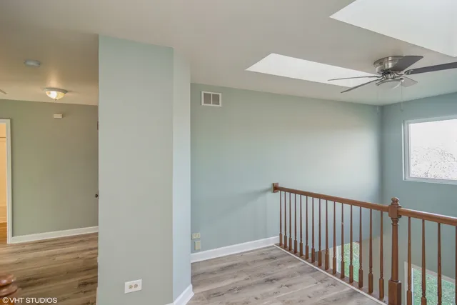 a view of a hallway with a chandelier fan and wooden floor