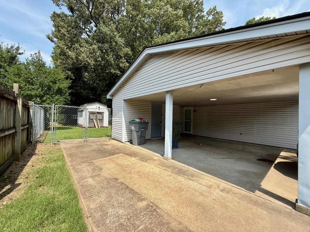2151 Bartlett Road Memphis, TN 38134 - Photo 23 of 27 View of parking / parking lot with concrete driveway, an attached carport, a storage unit, and a gate
