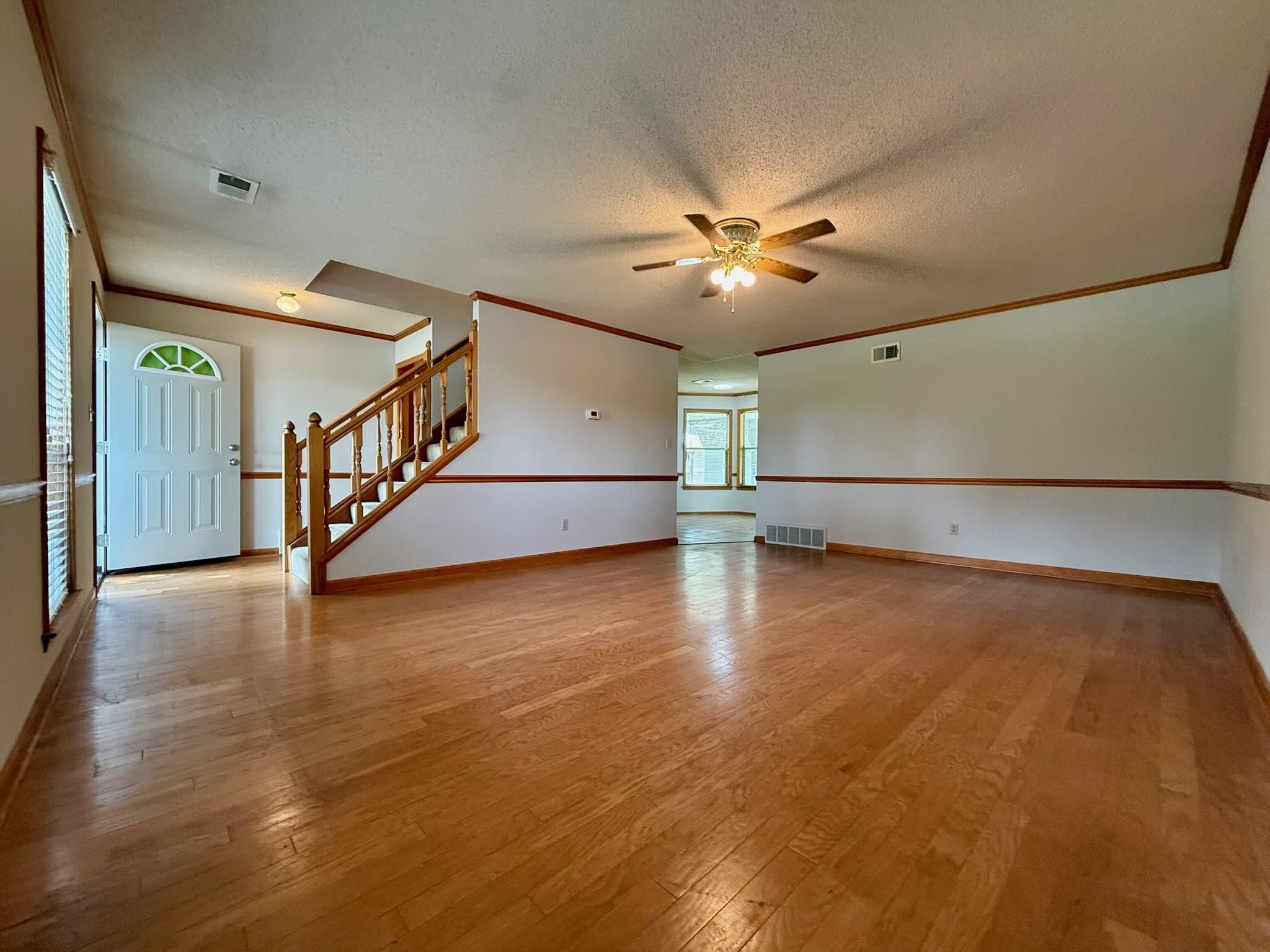 2151 Bartlett Road Memphis, TN 38134 - Photo 6 of 27 Unfurnished room featuring a ceiling fan, a textured ceiling, light wood-type flooring, stairs, and baseboards
