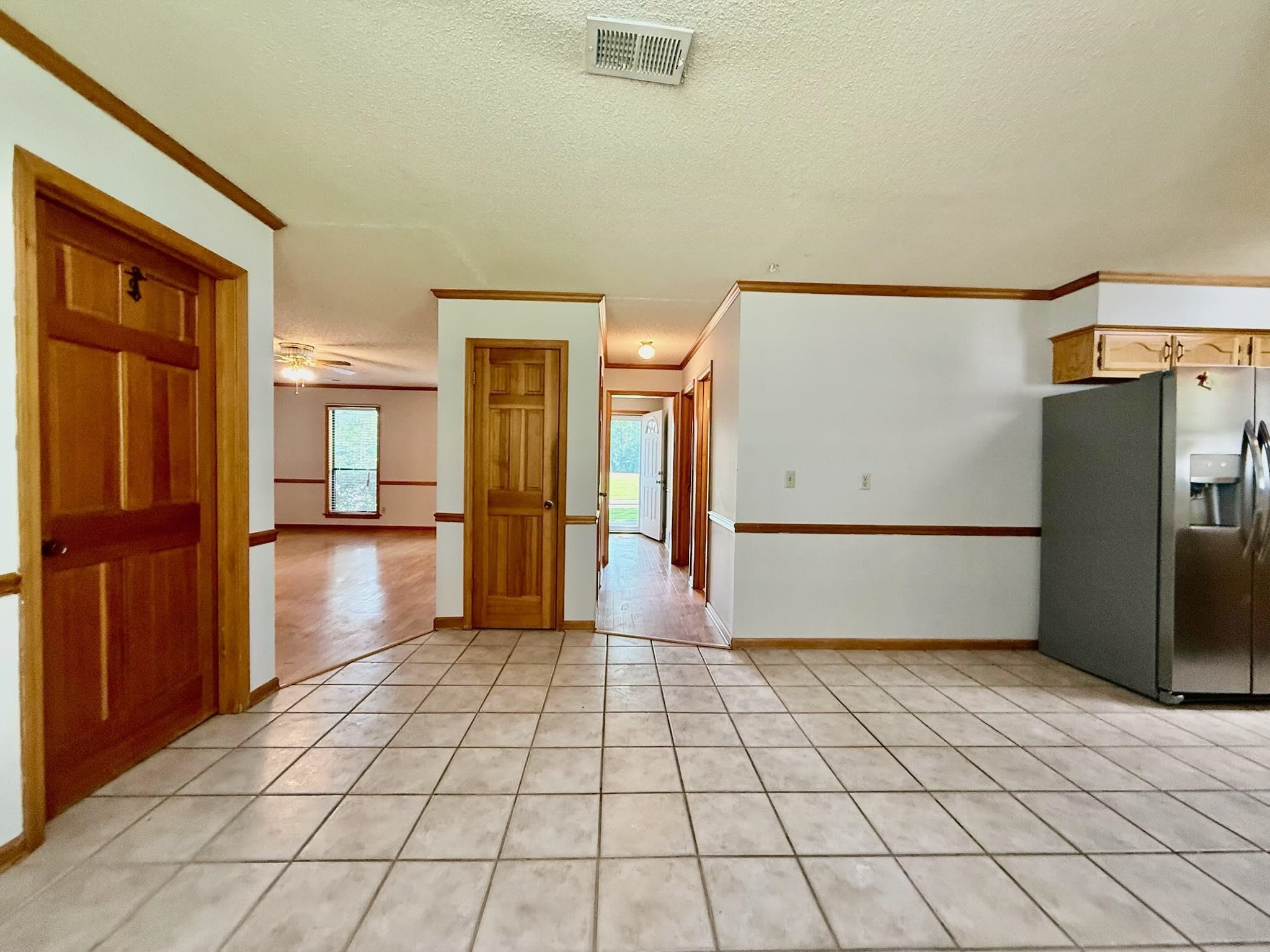 2151 Bartlett Road Memphis, TN 38134 - Photo 9 of 27 Kitchen with a ceiling fan, a textured ceiling, crown molding, light tile patterned flooring, and baseboards
