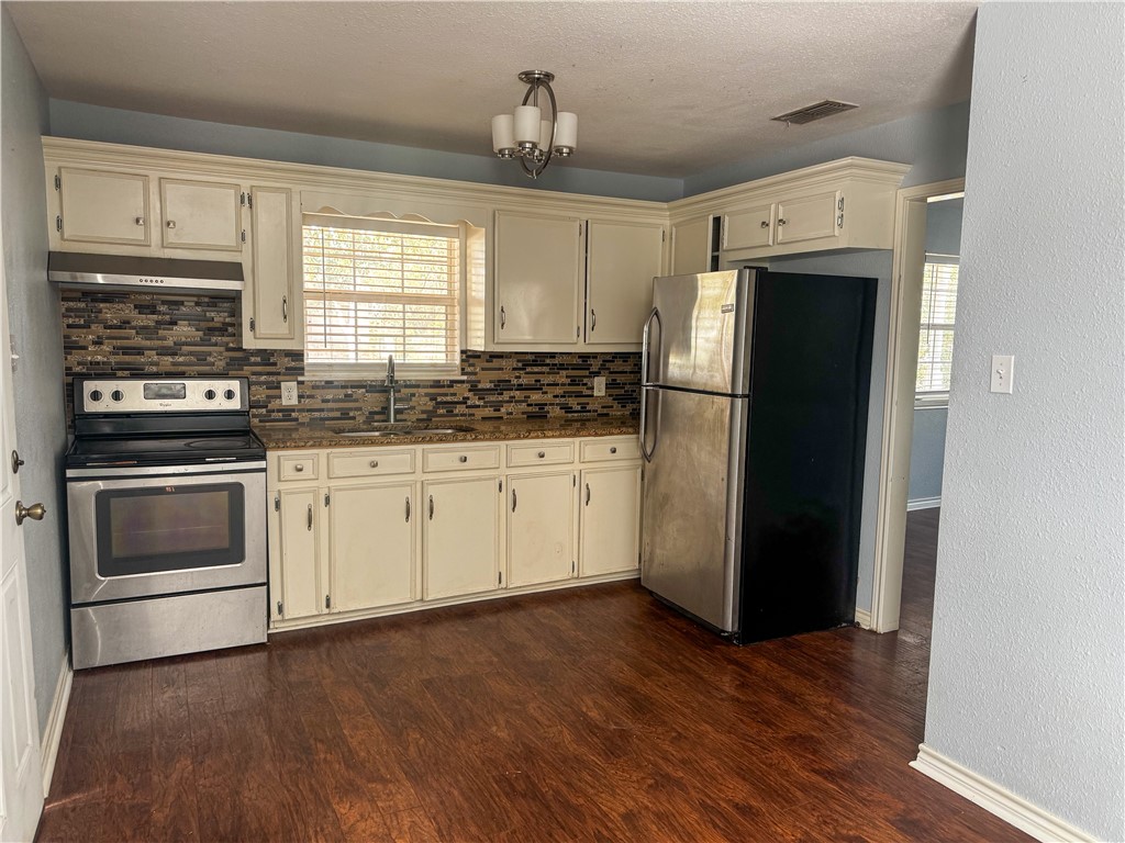 702 Jefferson Street Alice, TX 78332 - Photo 11 of 38 a kitchen with a refrigerator stove and wooden cabinets