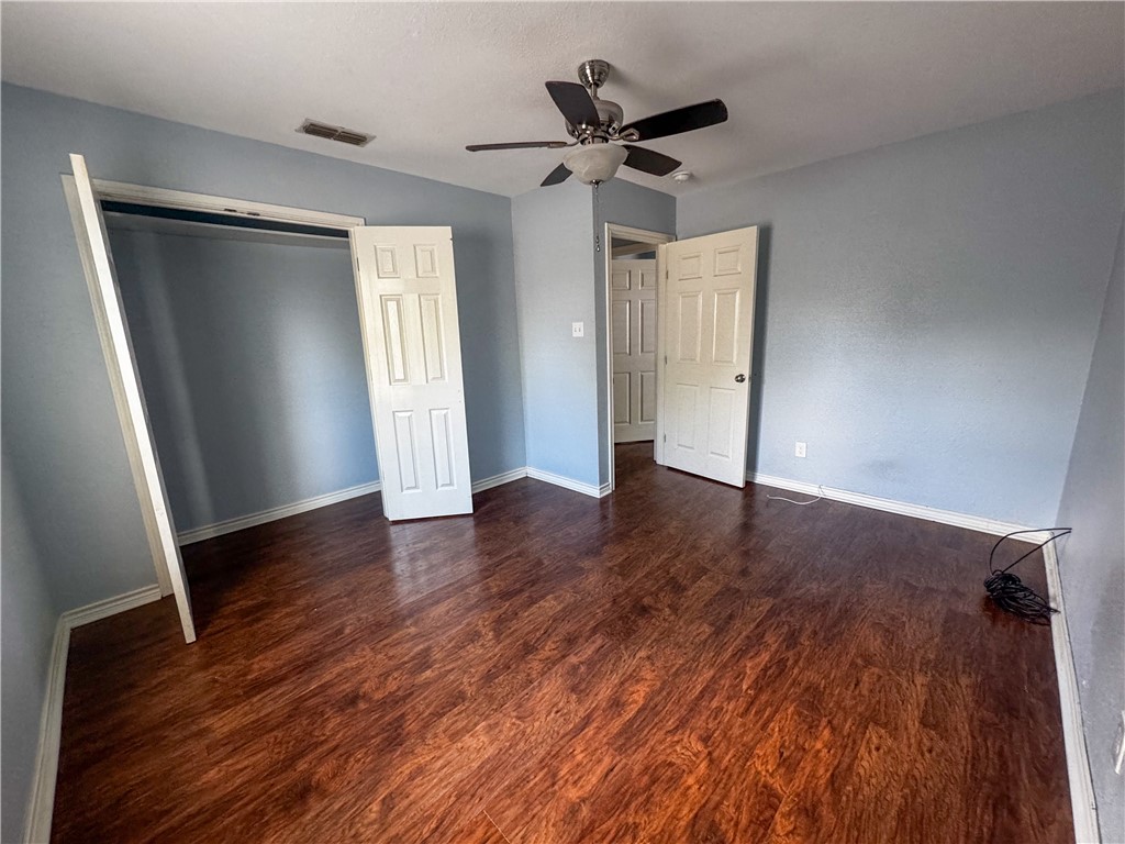 702 Jefferson Street Alice, TX 78332 - Photo 16 of 38 an empty room with wooden floor and a ceiling fan