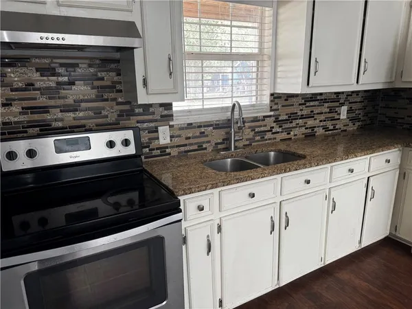 a kitchen with granite countertop white cabinets and appliances