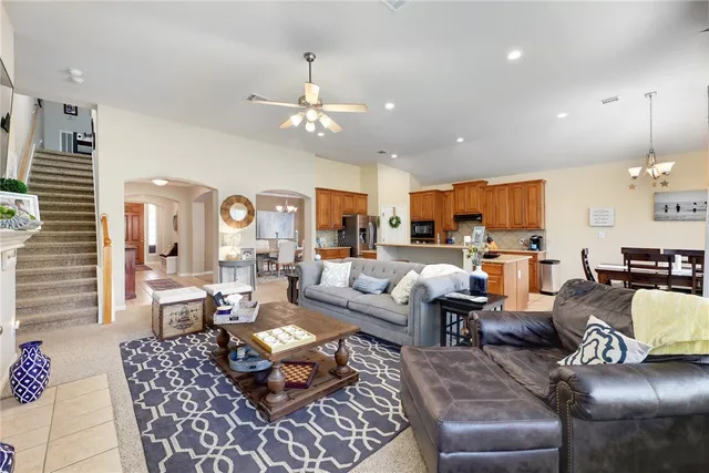a living room with furniture kitchen view and a chandelier