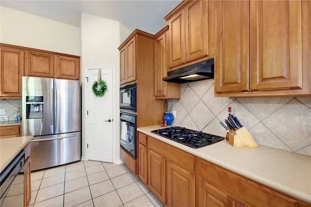 a kitchen with stainless steel appliances granite countertop a refrigerator and a stove top oven