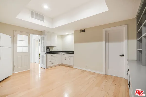 a large white kitchen with granite countertop a refrigerator and white cabinets