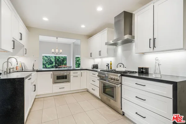a kitchen with granite countertop white cabinets white appliances a sink and a stove