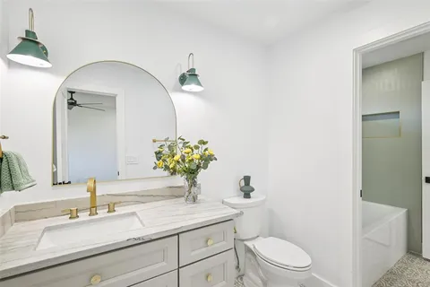 a bathroom with a granite countertop toilet sink and mirror