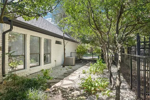 a backyard of a house with large trees and plants