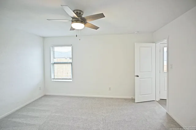 an empty room with a window and a fan