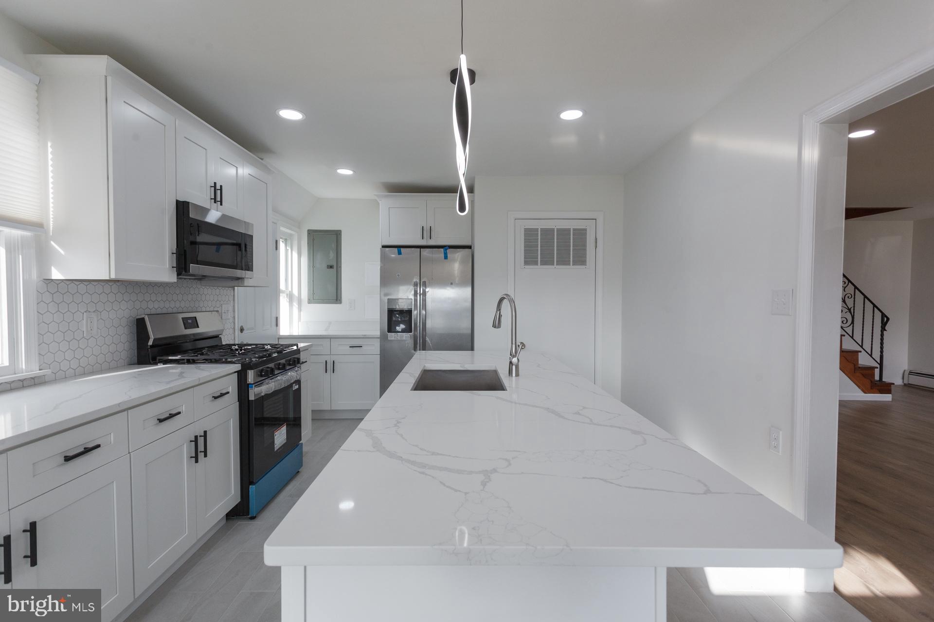 1007 Ripley Street Philadelphia, PA 19111 - Photo 10 of 27 a large white kitchen with kitchen island a sink appliances and a counter top space