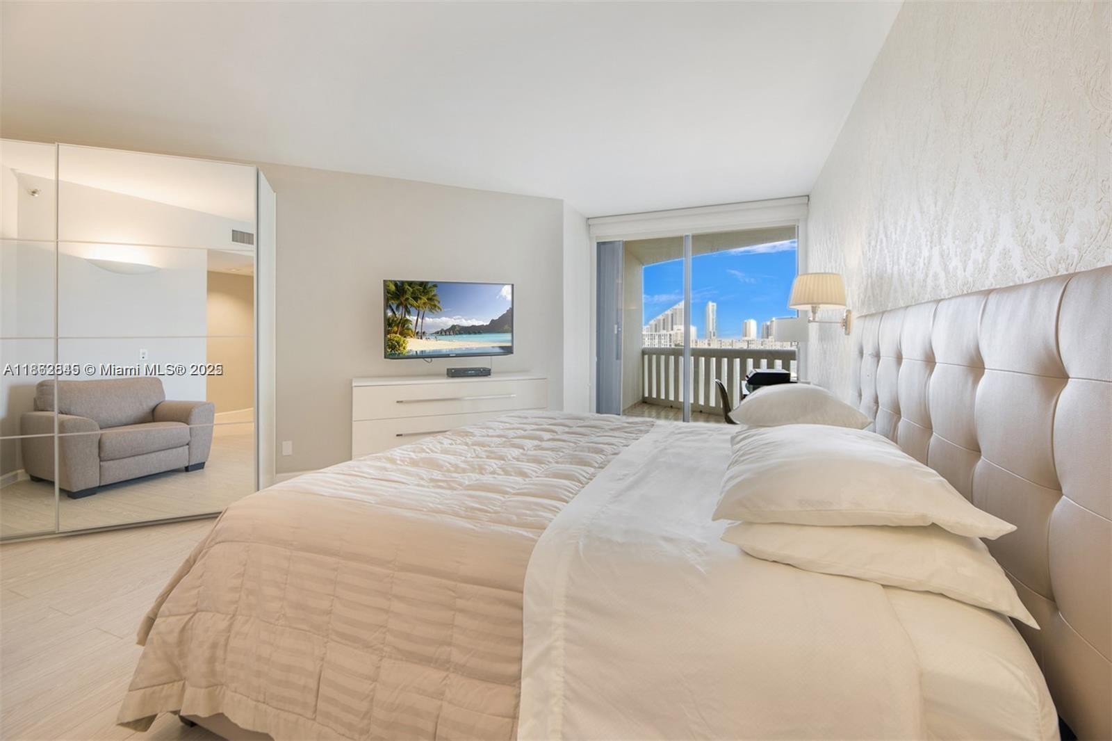 3000 East Island Boulevard, Unit 801 Aventura, FL 33160 - Photo 15 of 36 a bedroom with a large bed and a couch