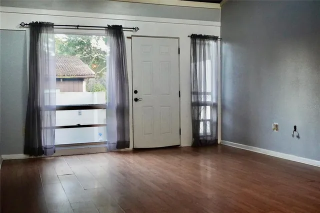 a view of an empty room with wooden floor and a window