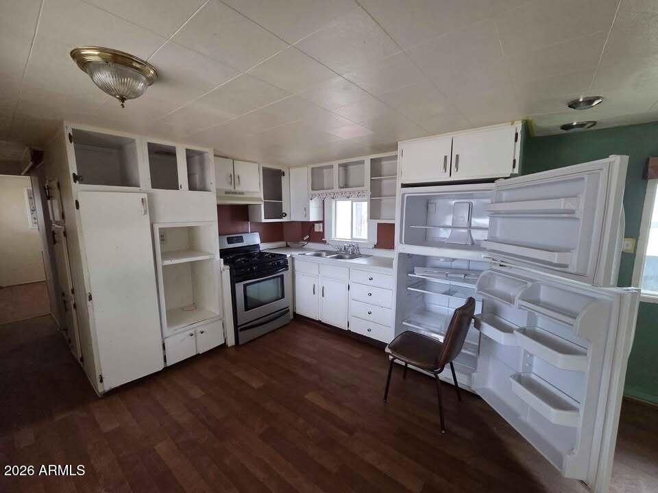 730 Tesota Quartzsite, AZ 85346 - Photo 11 of 15 a kitchen with stainless steel appliances kitchen island granite countertop a refrigerator a stove a sink dishwasher and white cabinets with wooden floor