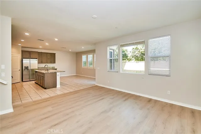 a kitchen with stainless steel appliances granite countertop a stove top oven a sink dishwasher and a refrigerator with wooden floor