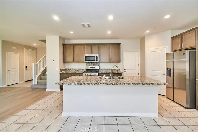 a large kitchen with stainless steel appliances granite countertop a stove a sink a refrigerator and a granite counter tops