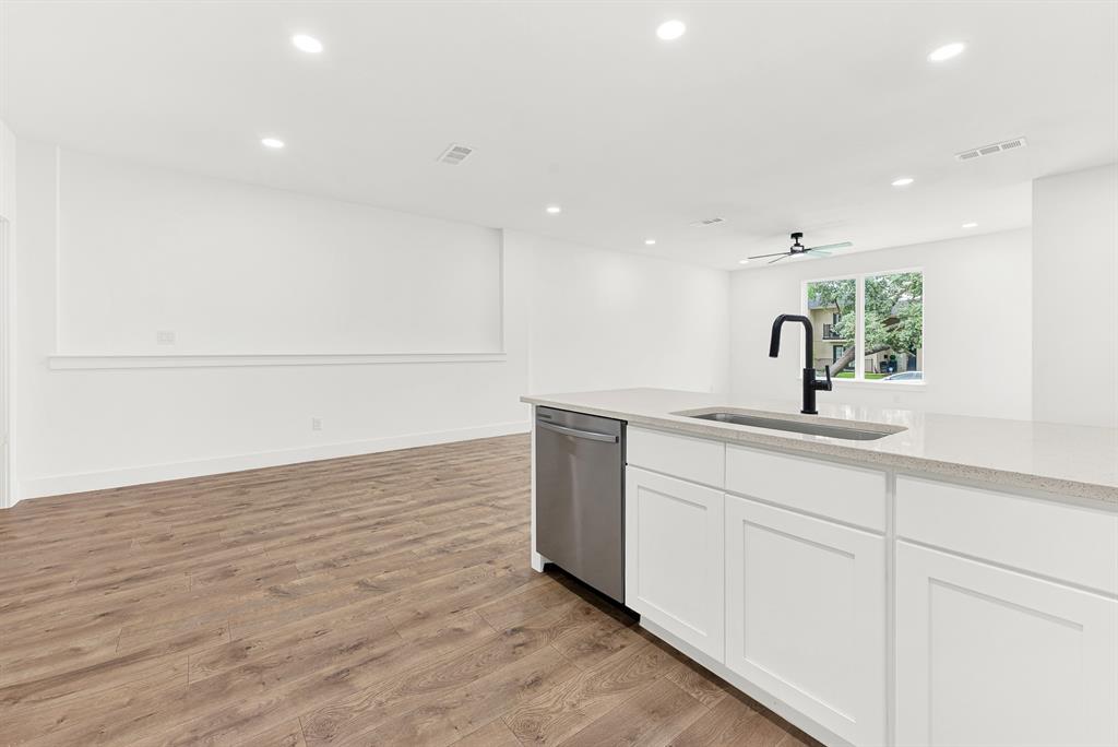 9471 Timberleaf Drive Dallas, TX 75243 - Photo 12 of 39 Kitchen island with a matte black faucet and undermount sink, stainless steel dishwasher, white cabinetry, and light-toned countertop