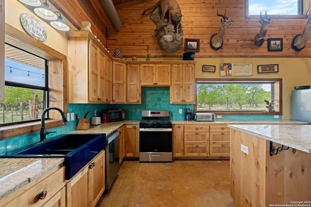 a kitchen with stainless steel appliances granite countertop a sink a stove and a wooden cabinets