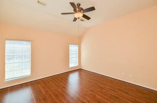 a view of empty room with wooden floor and fan