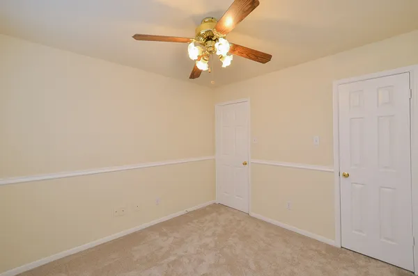 an empty room with a chandelier fan and windows
