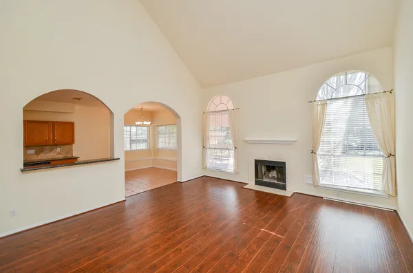 an empty room with wooden floor fireplace and windows