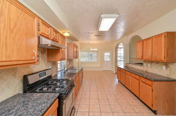 a kitchen with stainless steel appliances granite countertop a stove a sink and a microwave