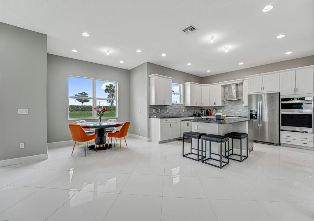 5482 Macoon Way Westlake, FL 33470 - Photo 18 of 69 a kitchen with stainless steel appliances kitchen island granite countertop a sink and a refrigerator