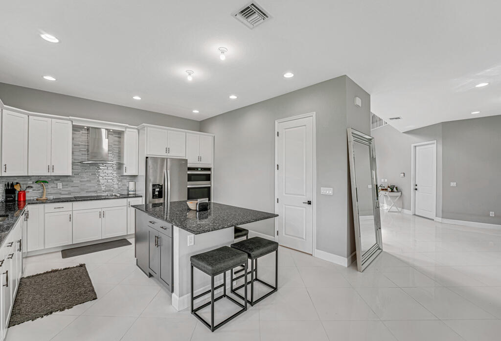 5482 Macoon Way Westlake, FL 33470 - Photo 51 of 69 a kitchen with stainless steel appliances granite countertop a stove refrigerator and a sink