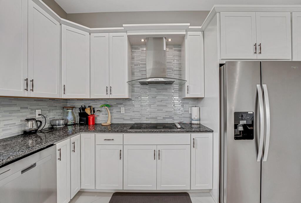 5482 Macoon Way Westlake, FL 33470 - Photo 52 of 69 a kitchen with stainless steel appliances granite countertop a refrigerator and white cabinets