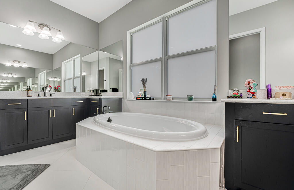 5482 Macoon Way Westlake, FL 33470 - Photo 58 of 69 a bathroom with a sink a large mirror and a bathtub