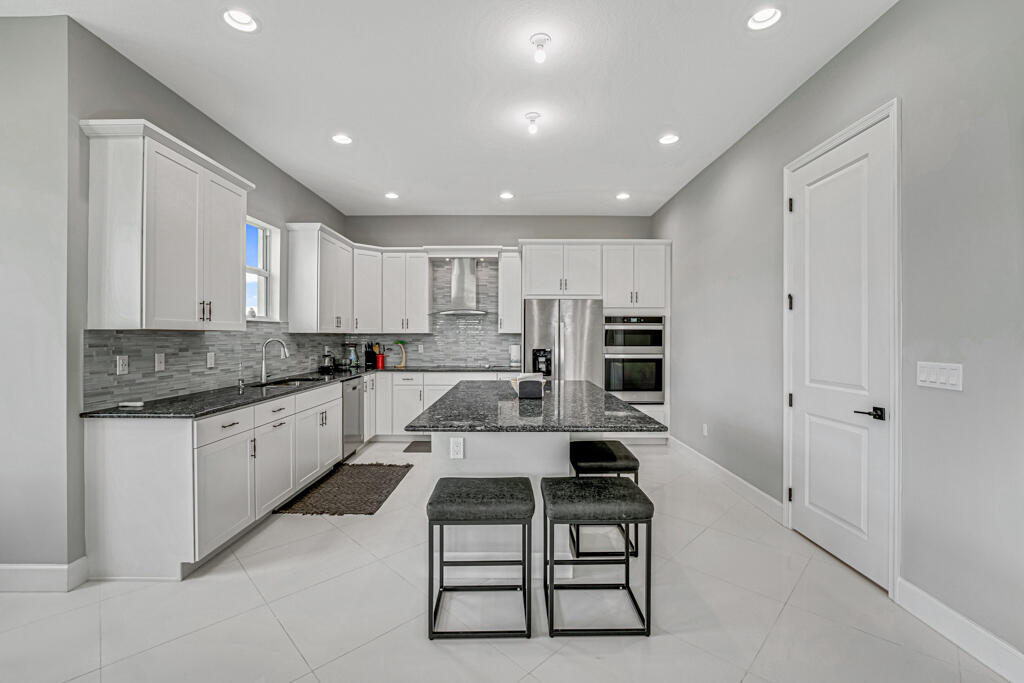 5482 Macoon Way Westlake, FL 33470 - Photo 7 of 69 a large white kitchen with stainless steel appliances granite countertop a stove a sink and a refrigerator