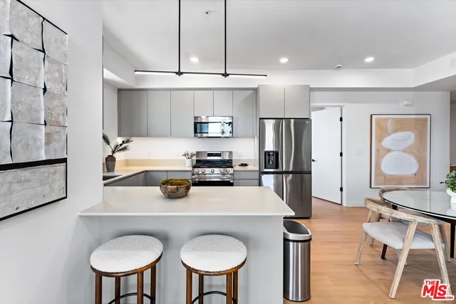 a kitchen with stainless steel appliances a dining table chairs and refrigerator