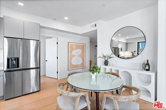 a very nice looking dining room with kitchen island a table chairs refrigerator and a wooden floor