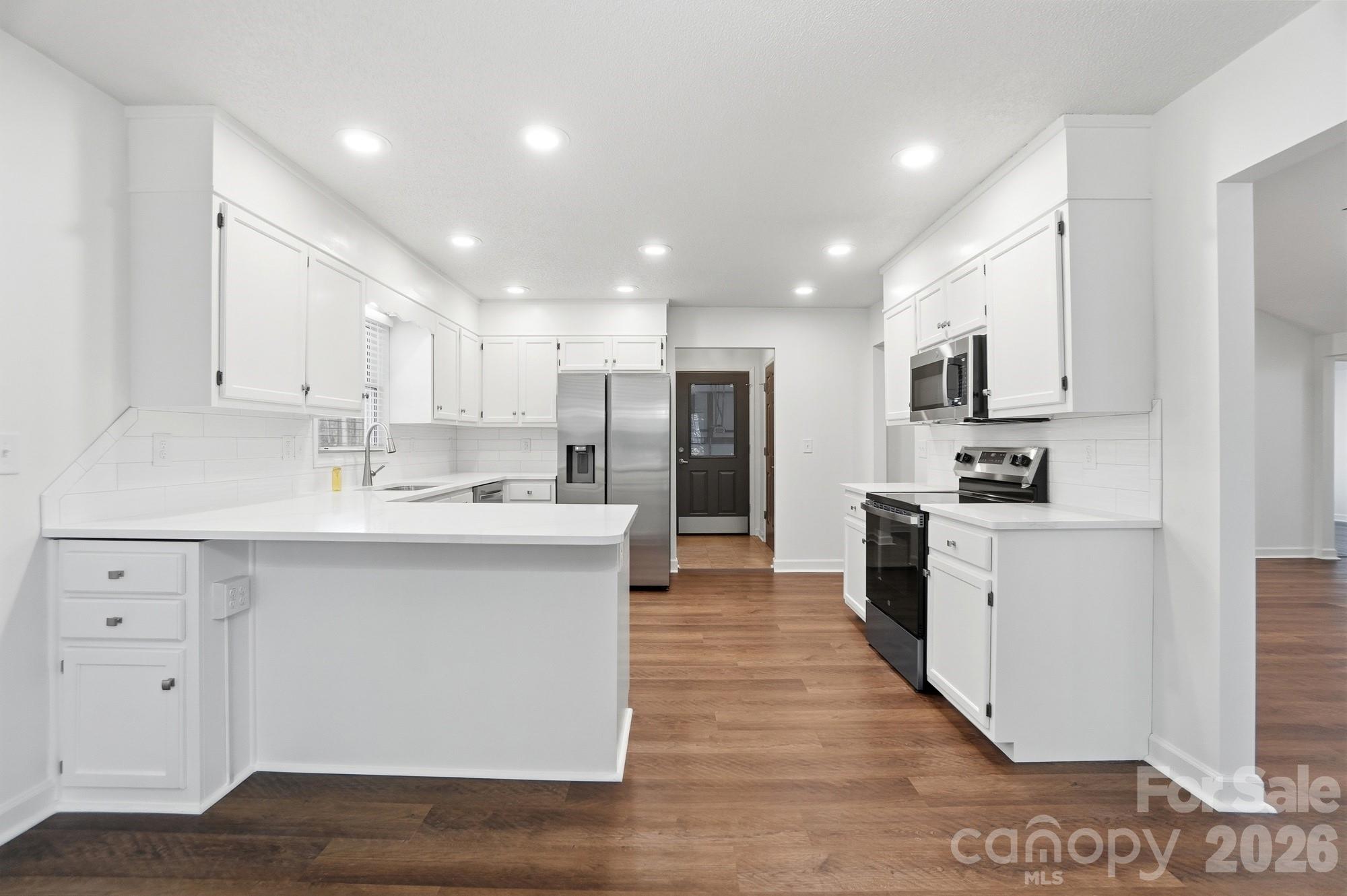 4437 Lake Shore Road North Denver, NC 28037 - Photo 10 of 43 a kitchen with stainless steel appliances kitchen island granite countertop a stove top oven a sink and white cabinets
