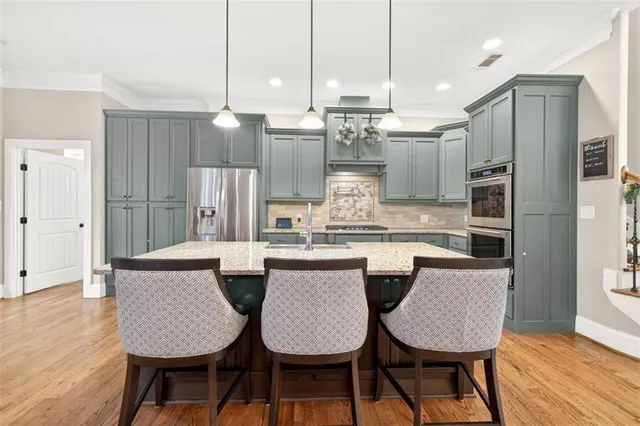 a kitchen with stainless steel appliances granite countertop a dining table chairs and wooden floor